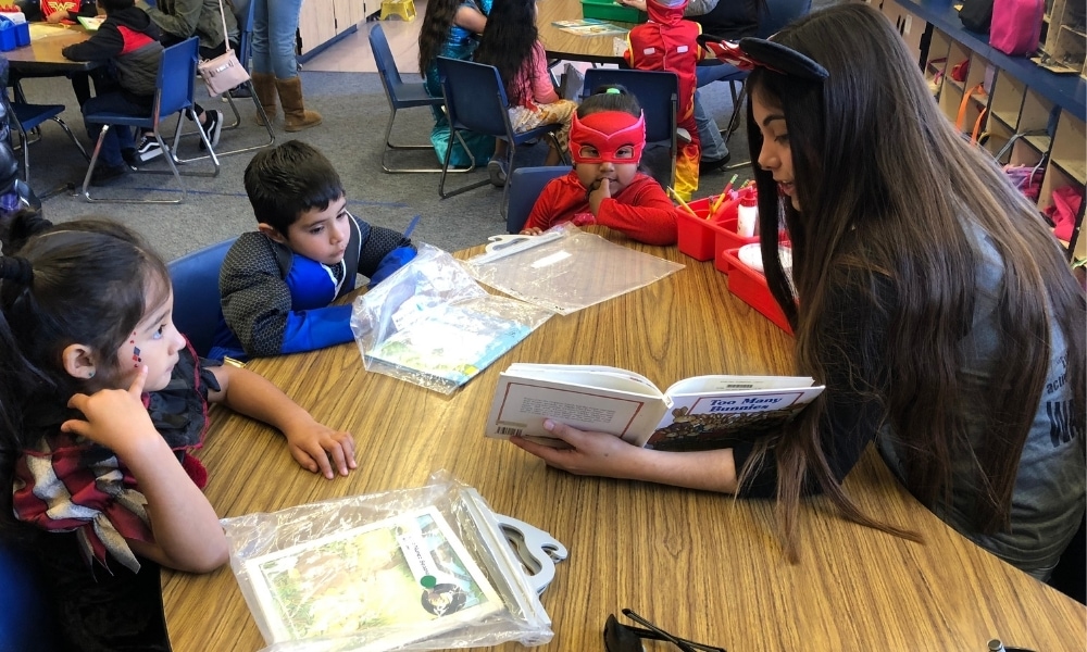 teen volunteer reading to elementary school kids